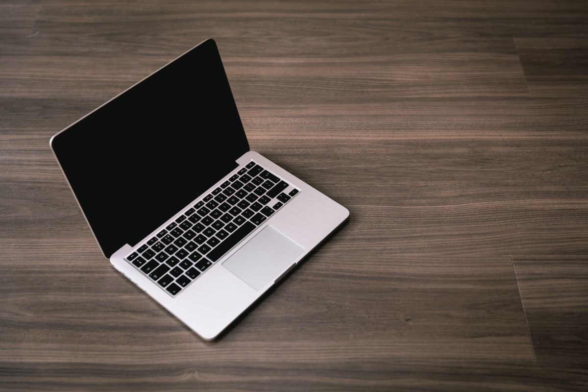 Otwarty laptop z czarnym, wyłączonym ekranem na drewnianym blacie