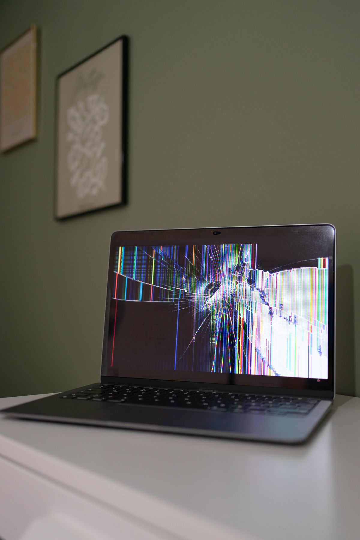 Laptop z pękniętą matrycą pokrytą kolorowymi paskami zakłóceń