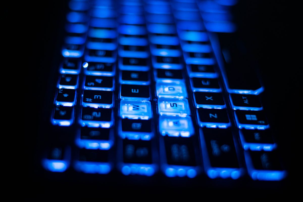 Podświetlona na niebiesko klawiatura laptopa na ciemnym tle