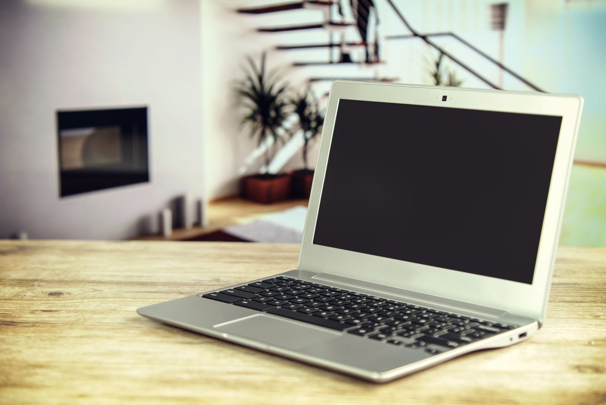 Srebrny, smukły laptop na drewnianym blacie