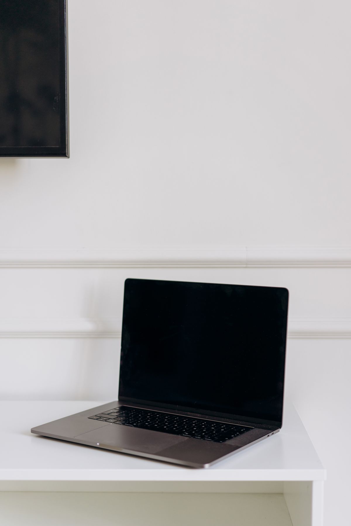 Szary, zamknięty laptop na białym biurku