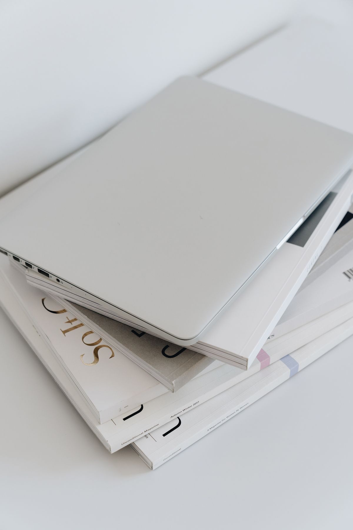 Zamknięty biały laptop na stosie białych magazynów