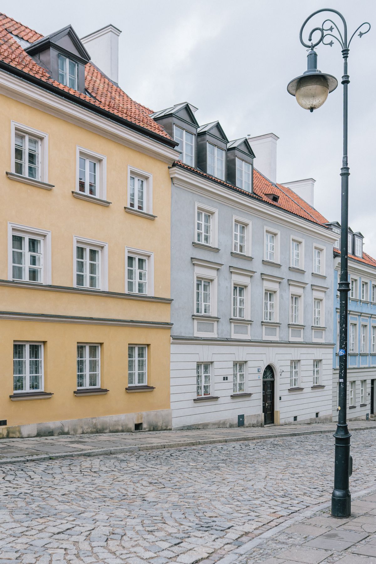 Kamienice w odcieniach żółci i szarości przy brukowanej ulicy