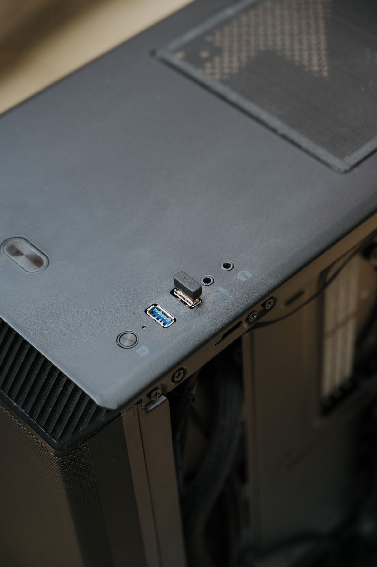 Zbliżenie górnego panelu obudowy komputera z przyciskiem power i portami USB