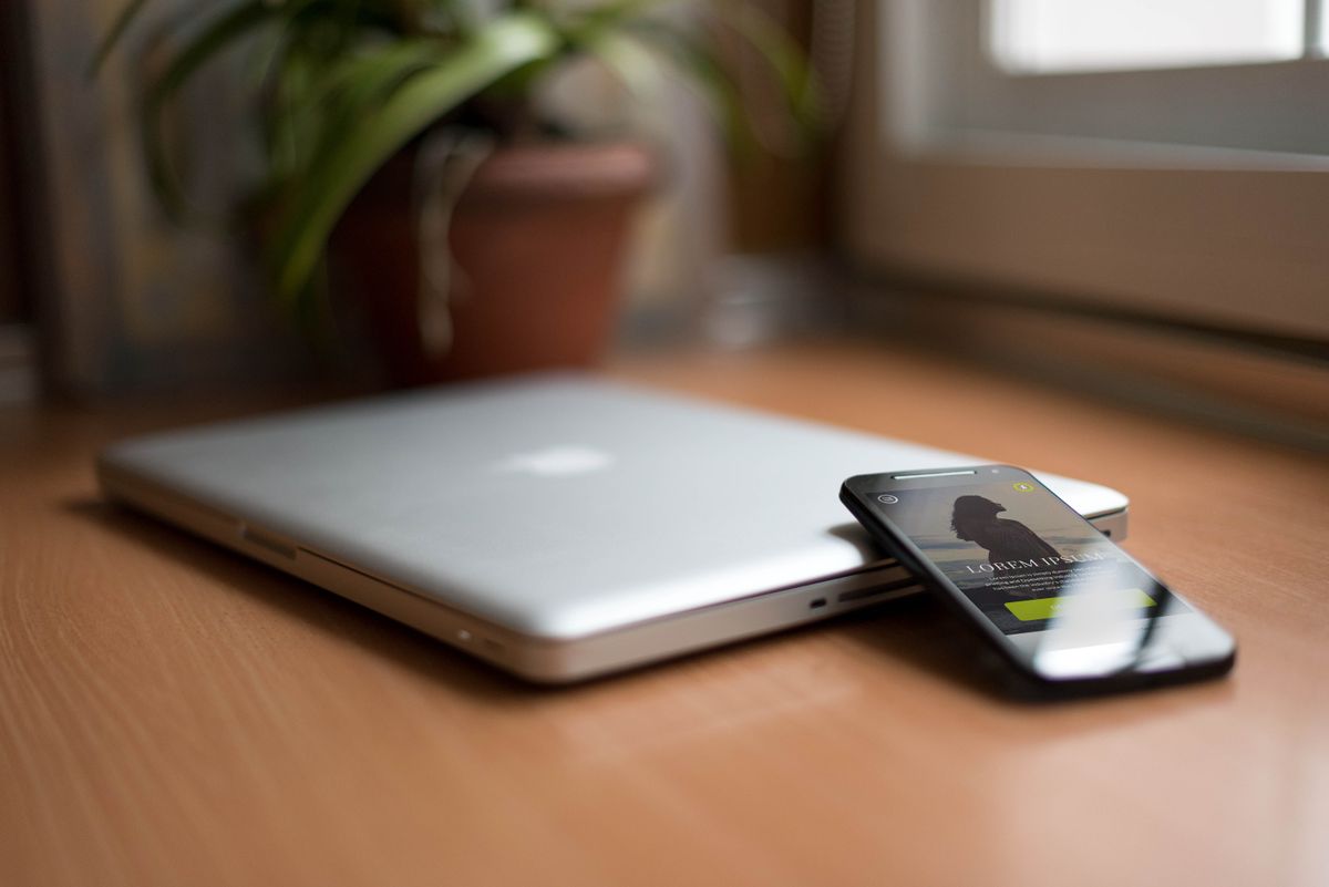 Zamknięty laptop i leżący na nim smartfon na drewnianym biurku