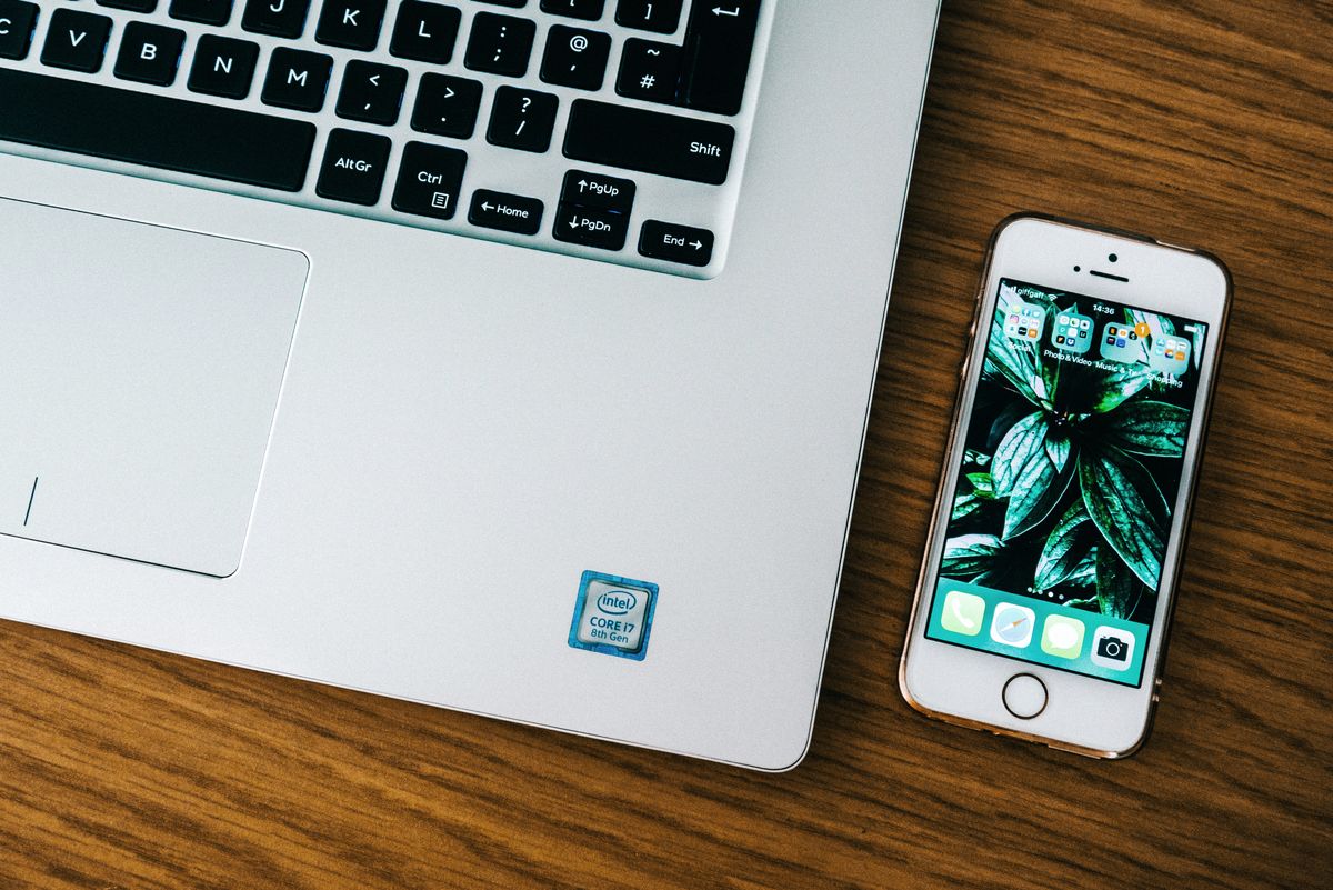 Róg klawiatury laptopa i leżący obok smartfon na blacie biurka