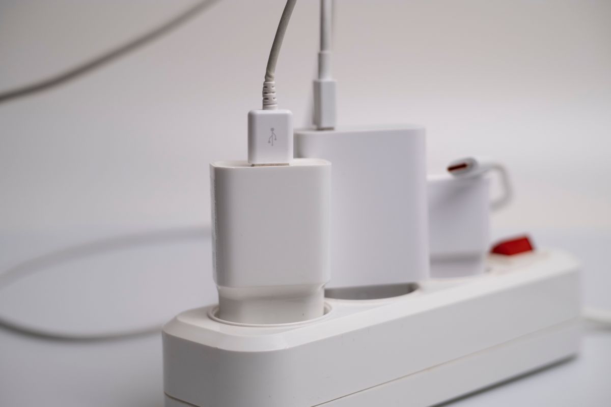 Biała listwa zasilająca z podłączonymi ładowarkami i kablami USB